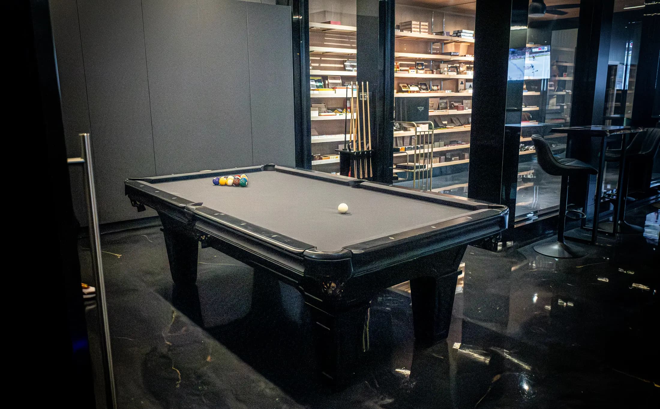 The billiards table with the humidor wall behind it
